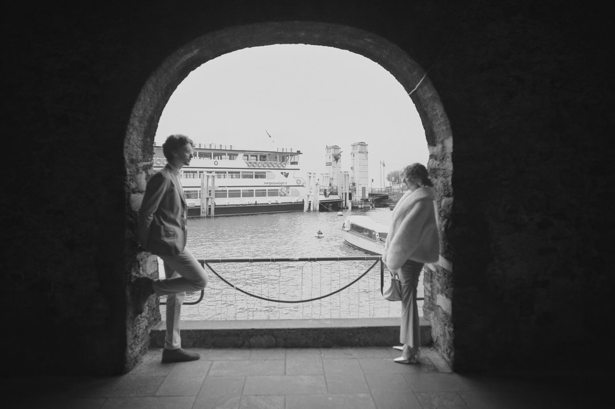 Couple photographed through a stone arch in Varenna
