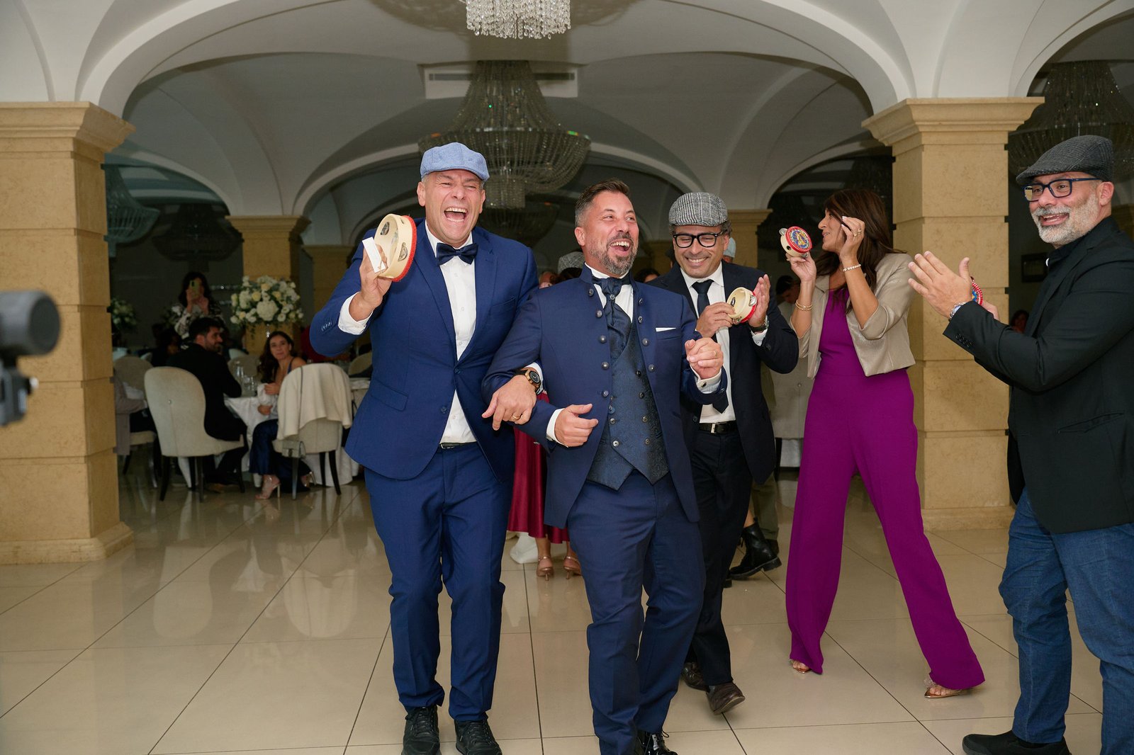 Alessandro laughing with tambourine players during the wedding reception at Villa Vittoria in Boscotrecase.