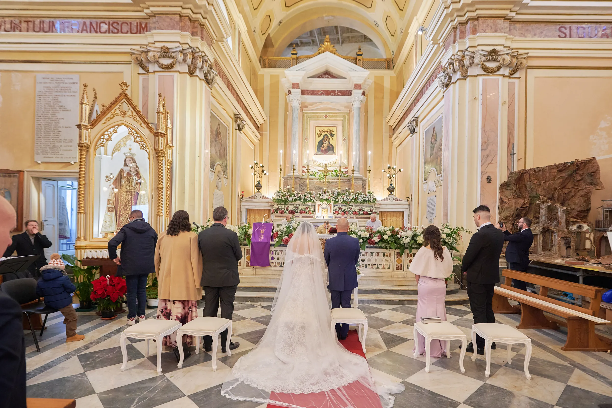 Wide view of Ciro and Rosa’s wedding ceremony inside the sanctuary in Gragnano, with Rosa’s lace train in the foreground.