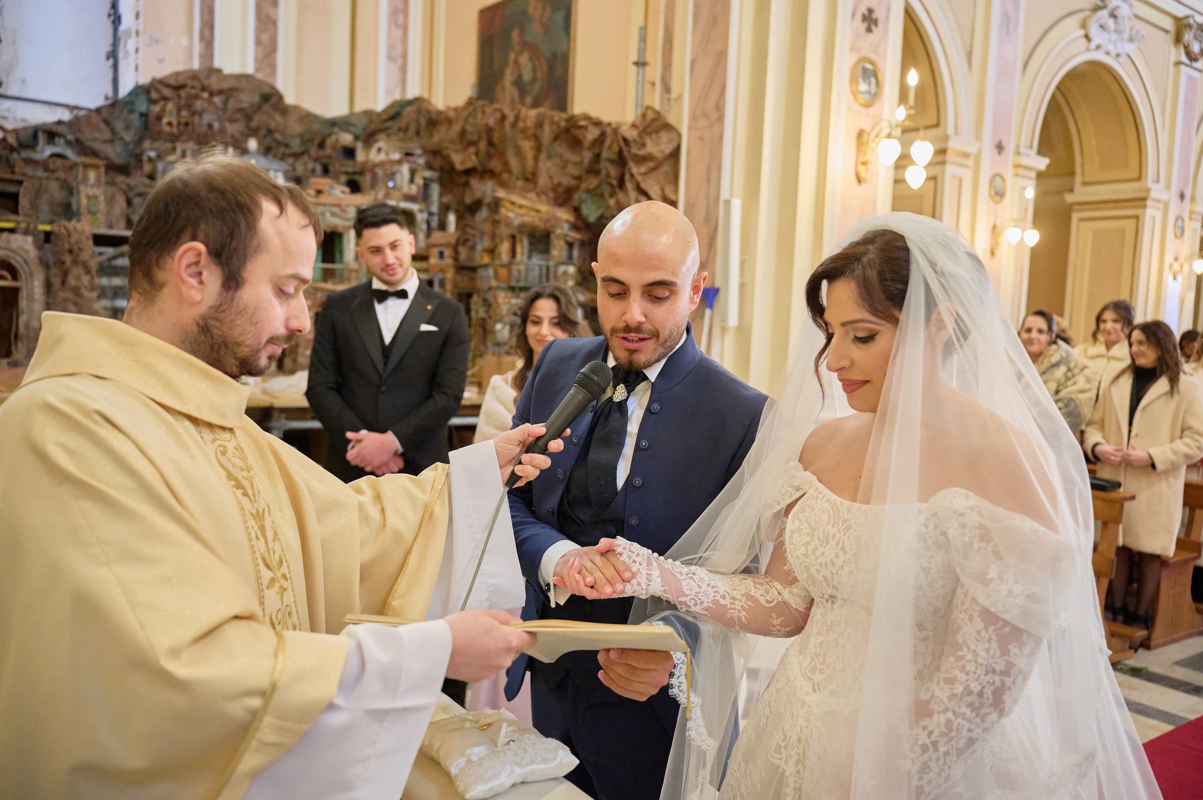 Ciro and Rosa joining hands beside the priest during their wedding vows at the sanctuary in Gragnano.