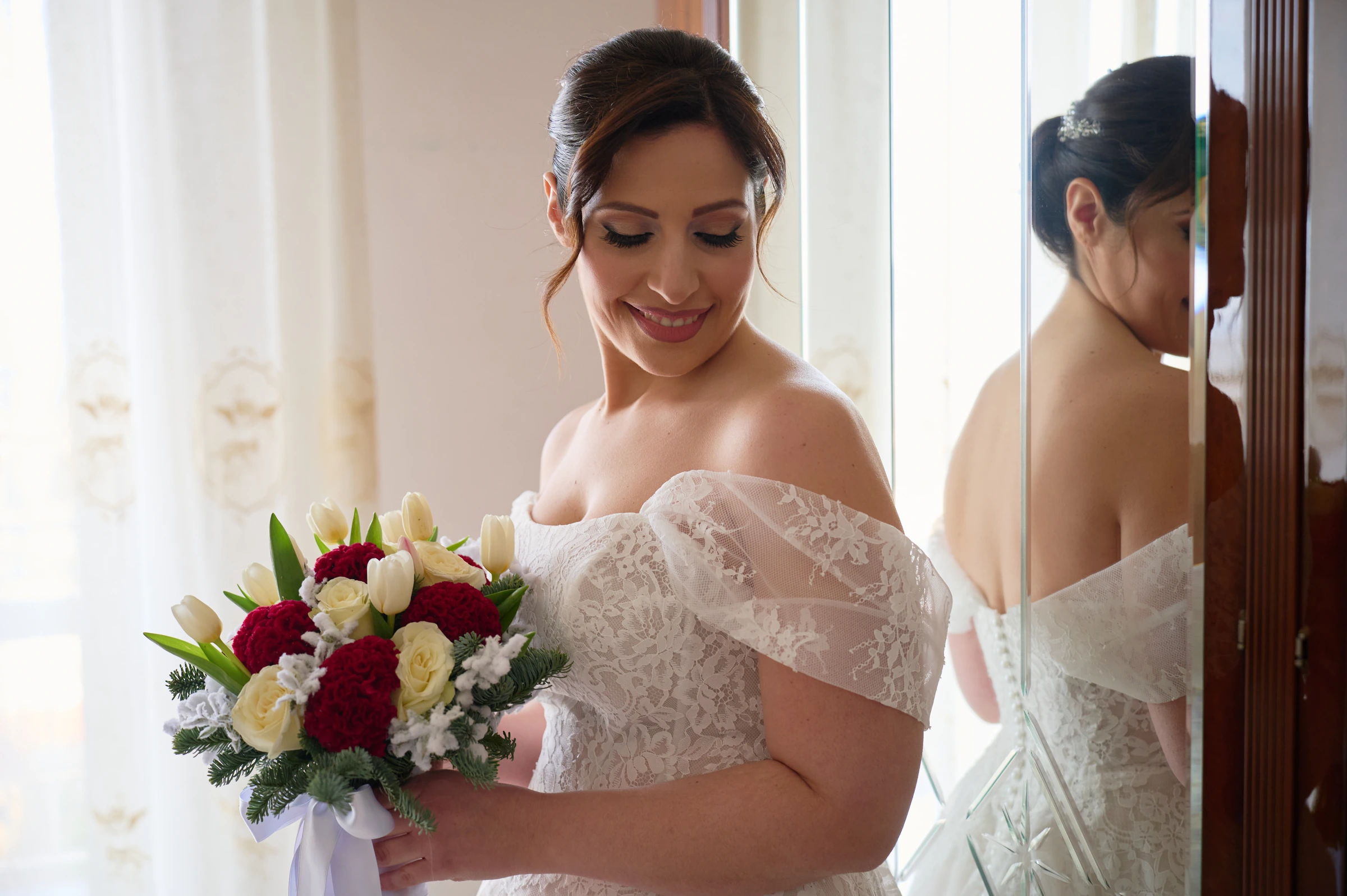 Rosa holding her red and white bridal bouquet beside a mirror during her wedding preparations.