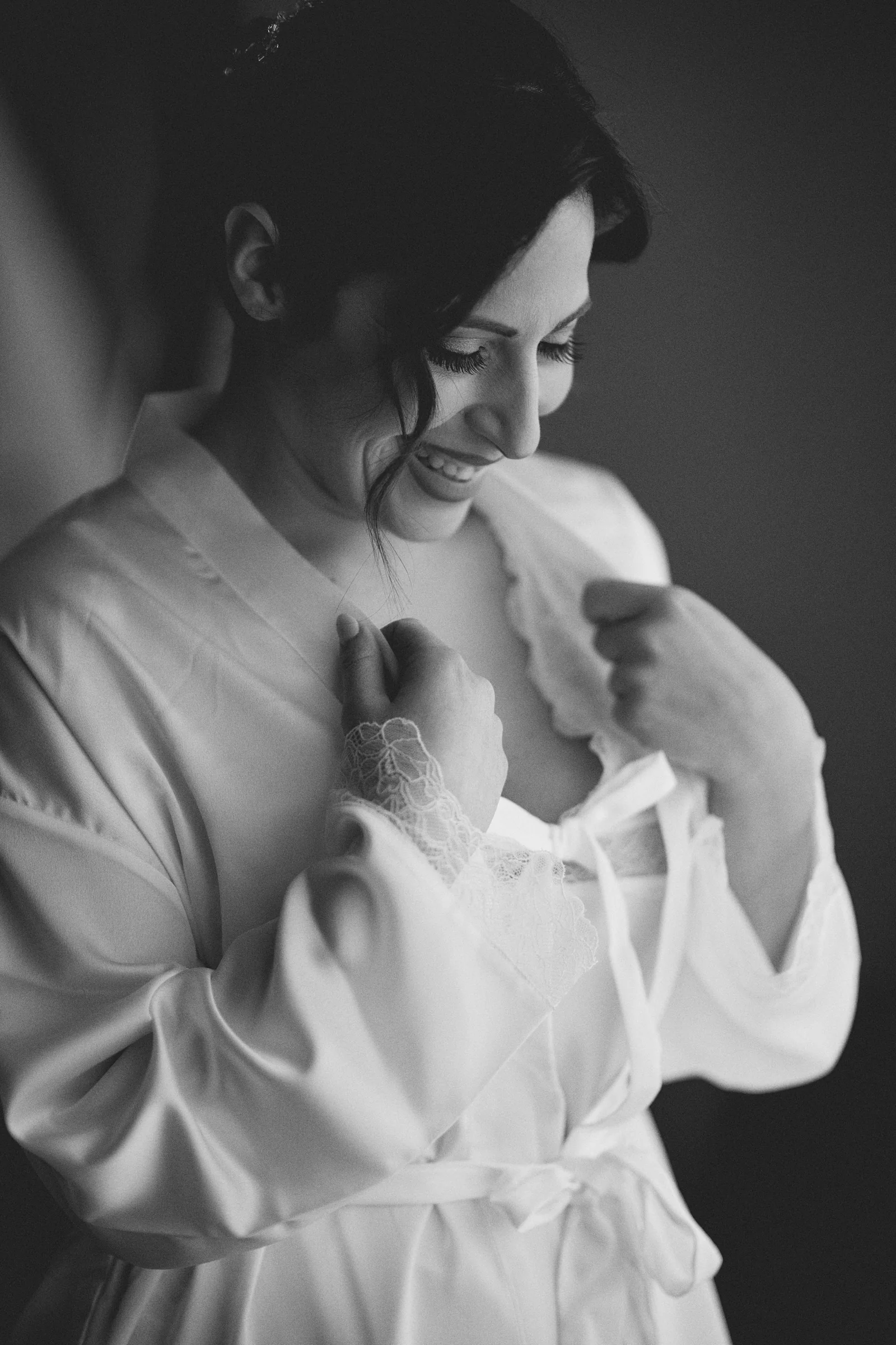 Rosa looking down and holding the lapels of her bridal robe in a black and white portrait before the ceremony.