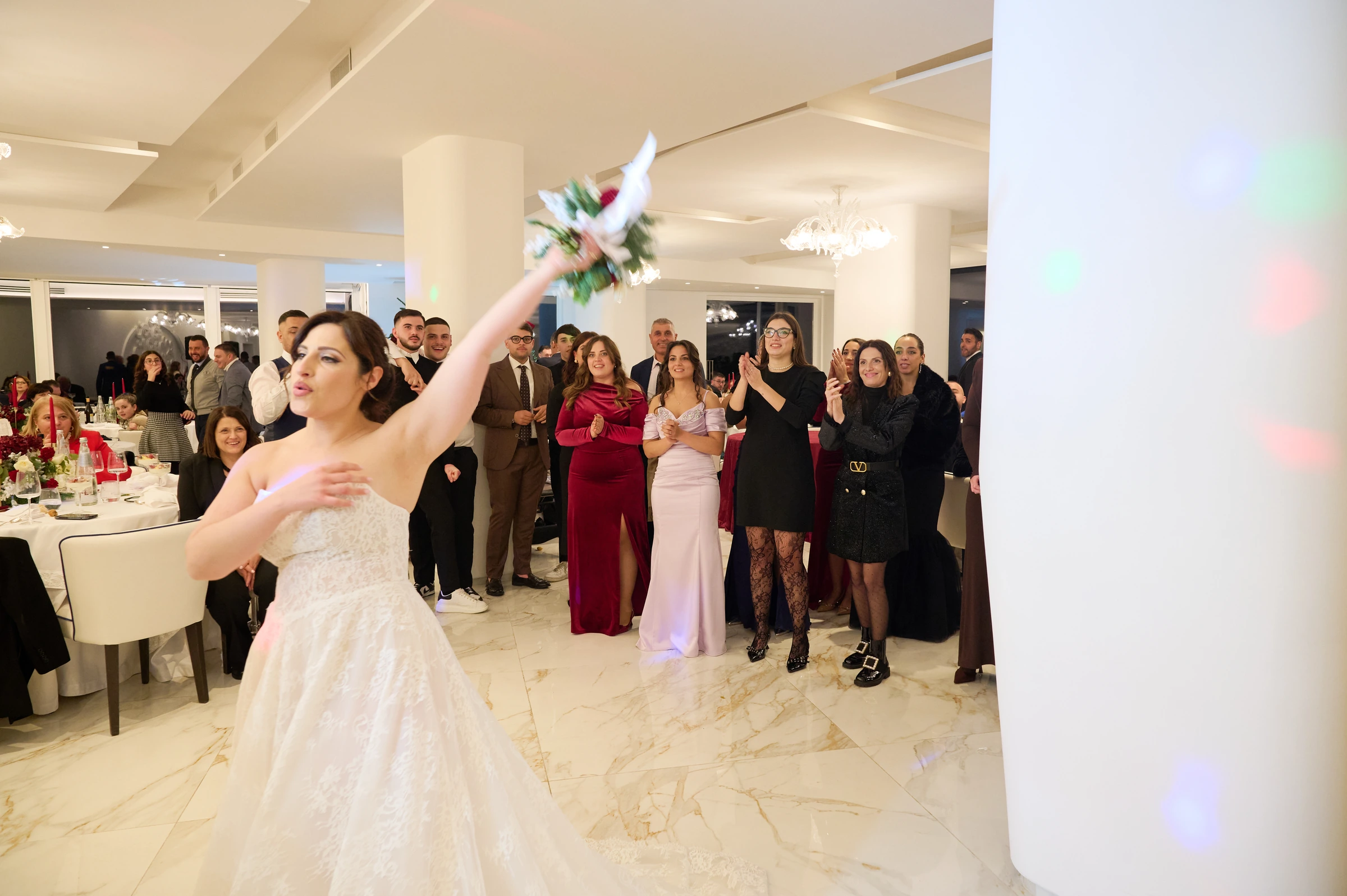 Rosa tossing her bridal bouquet as guests watch at Le Rocce in Agerola.