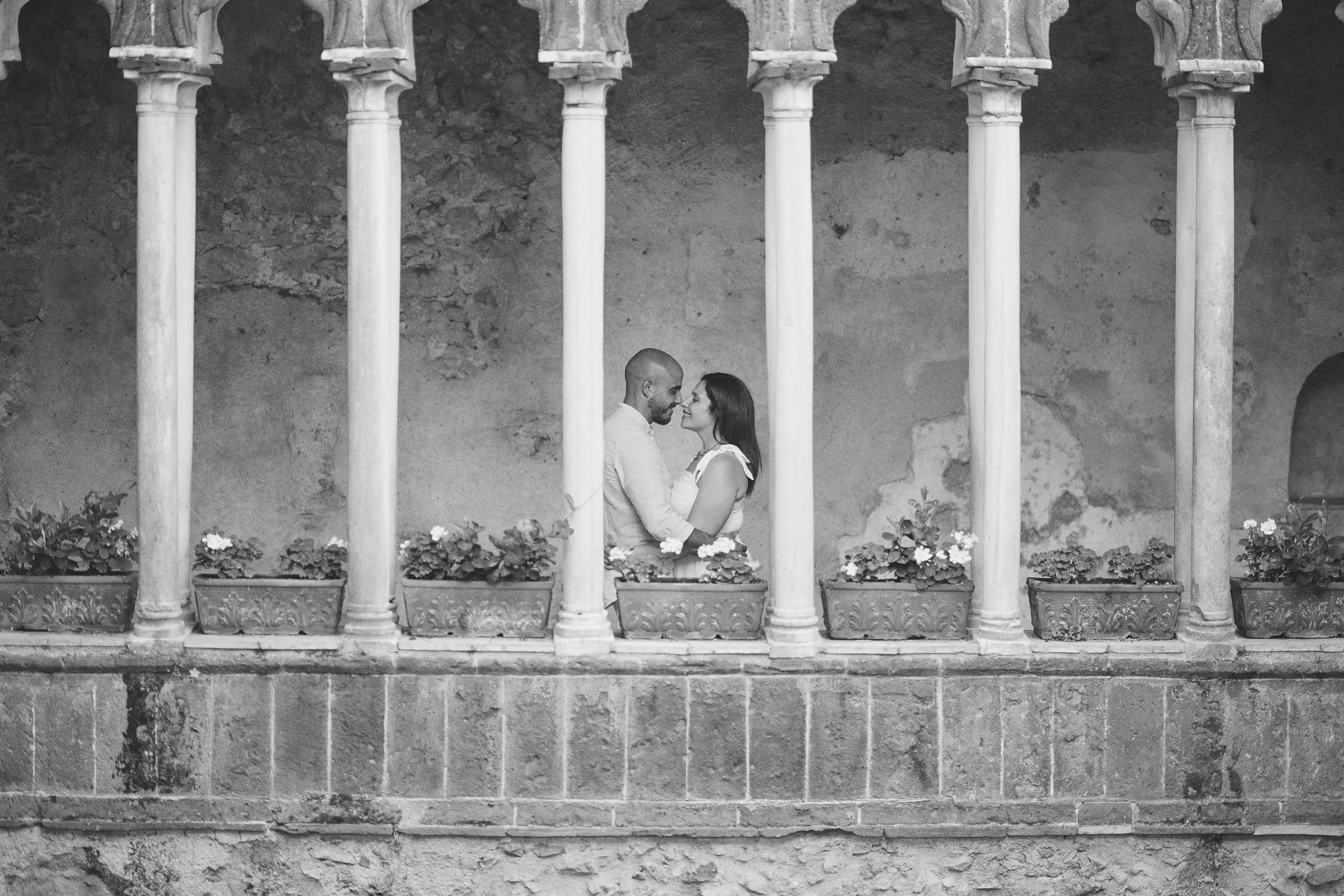 Ciro and Rosa embracing between the cloister columns at Villa Rufolo, Ravello, in black and white.