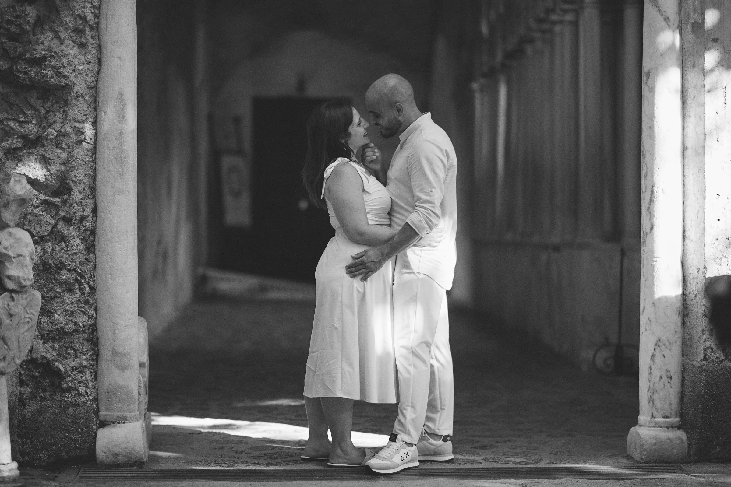 Ciro and Rosa embracing in a stone doorway during their engagement session at Villa Rufolo, Ravello.