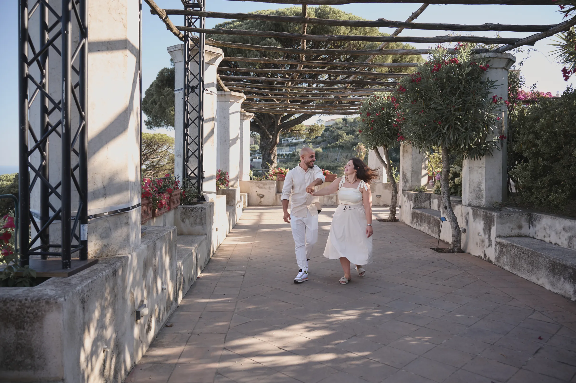 Ciro and Rosa walking hand in hand beneath a pergola during their engagement photoshoot in Ravello.
