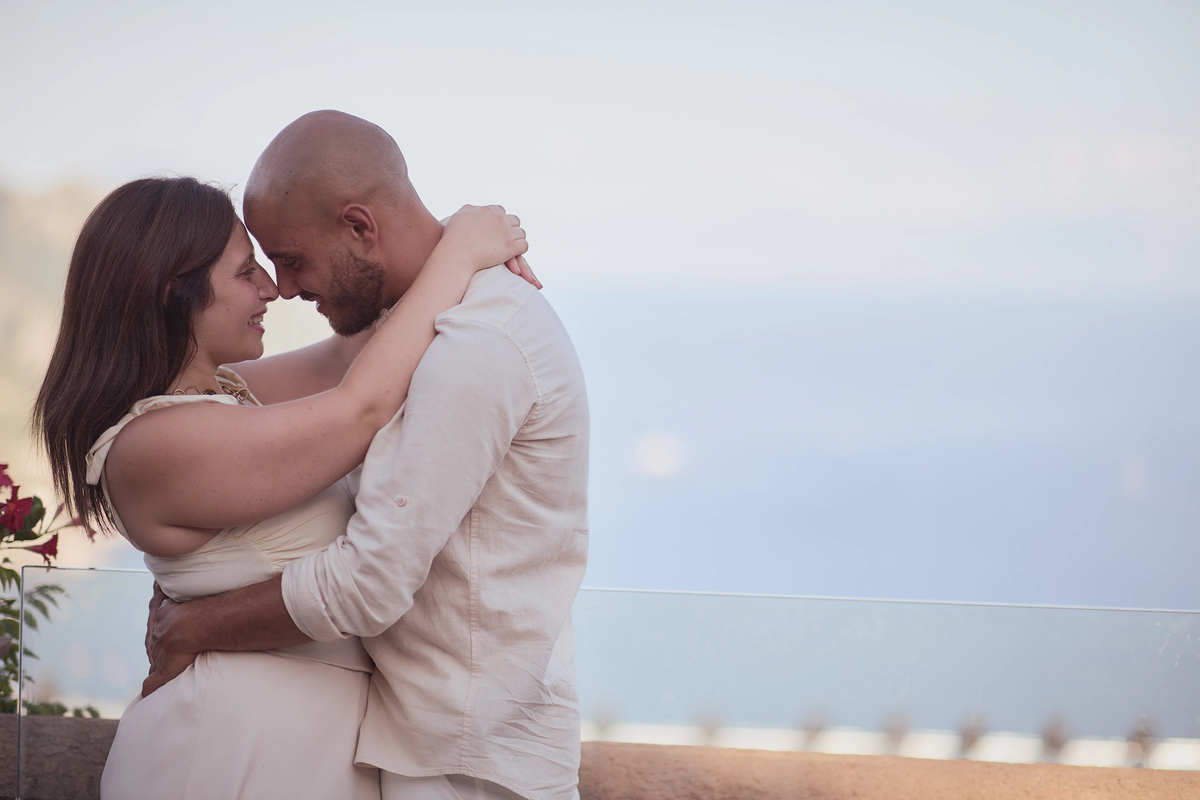 Ciro and Rosa touching foreheads beside the balustrade at Villa Rufolo, with the sea behind them.
