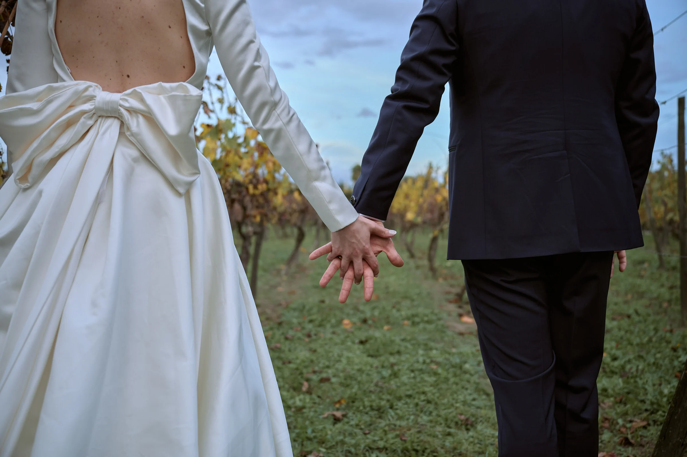 Close-up of the couple’s joined hands and Clementina’s dress bow in the vineyard at Bosco de’ Medici, Pompei.
