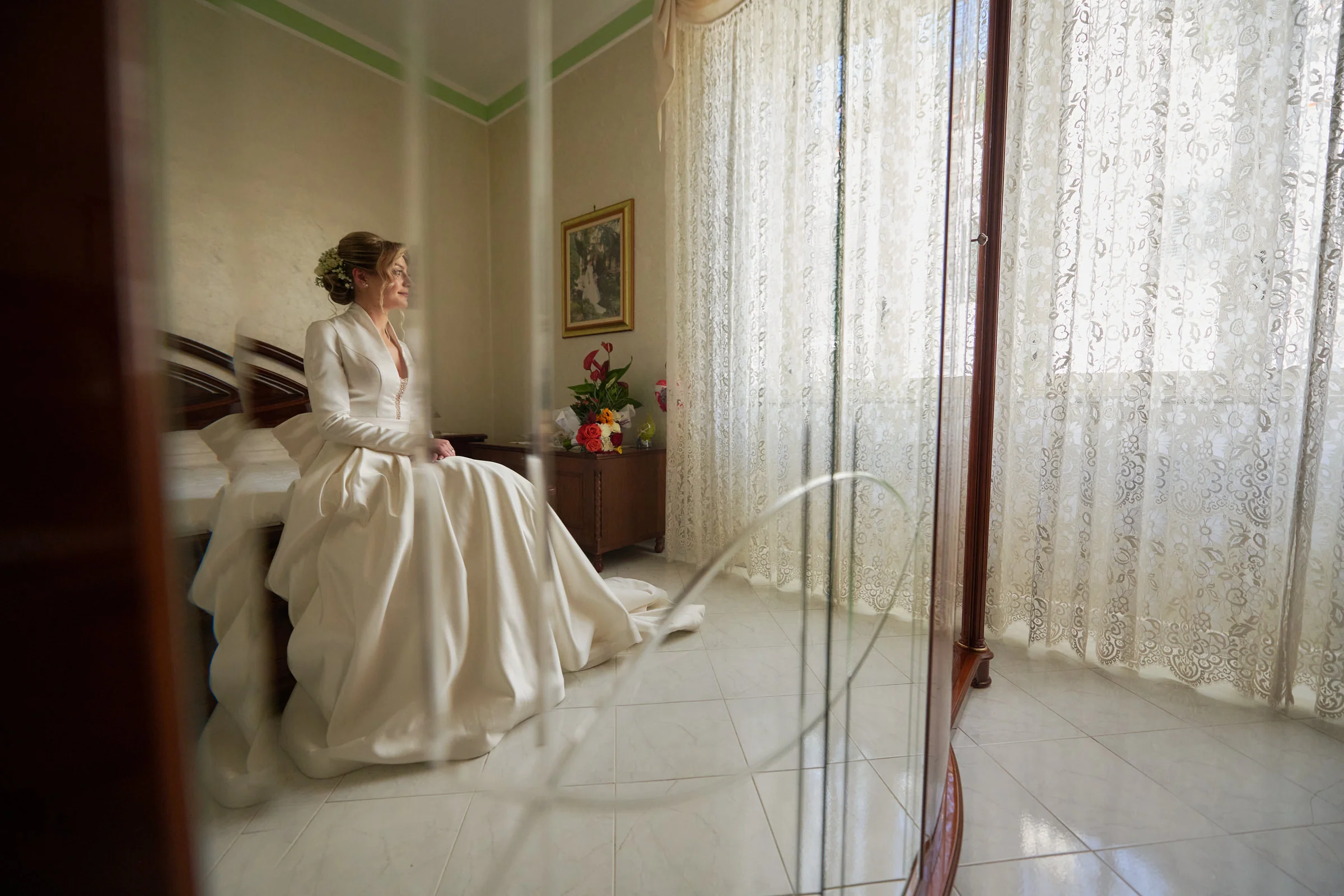 Clementina seated in her wedding dress, reflected in a mirror during preparations in Gragnano.