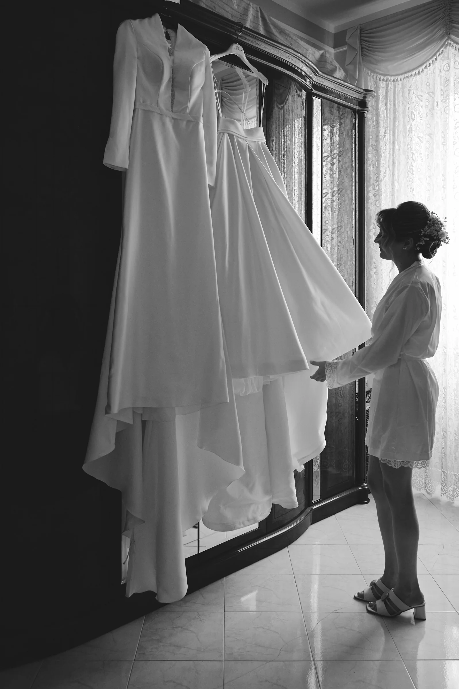 Black and white photograph of Clementina beside her hanging wedding dress in Gragnano.