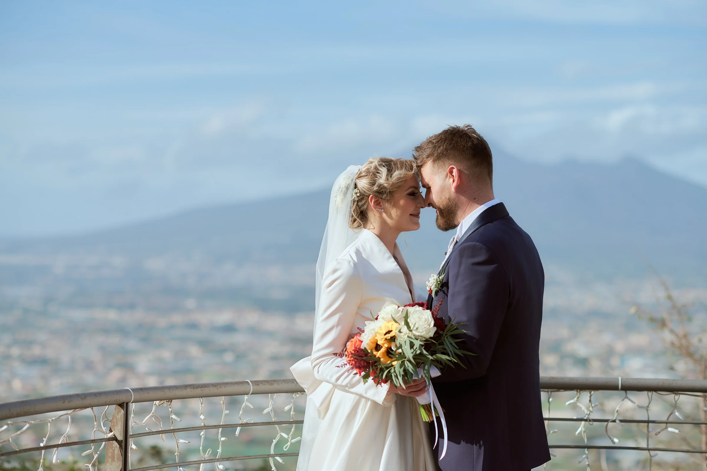 Matteo and Clementina touching foreheads with Mount Vesuvius in the background, in Gragnano.