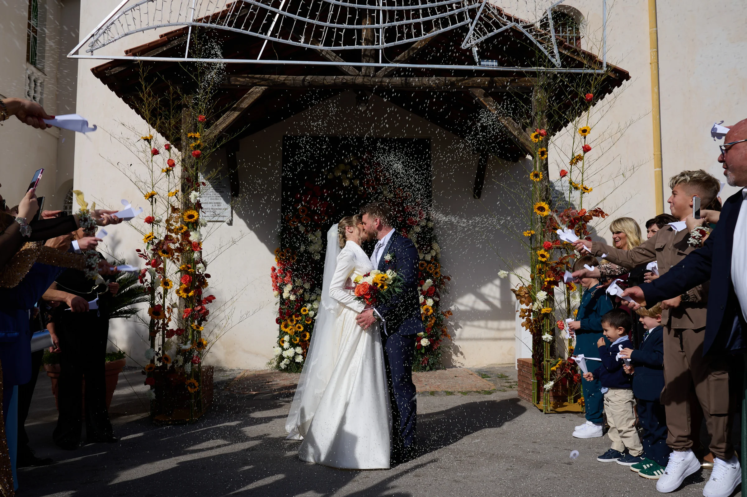 Matteo and Clementina kissing as guests shower them with rice in Gragnano.